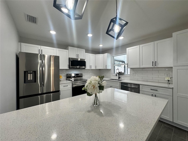 kitchen featuring backsplash, sink, light stone countertops, white cabinetry, and stainless steel appliances