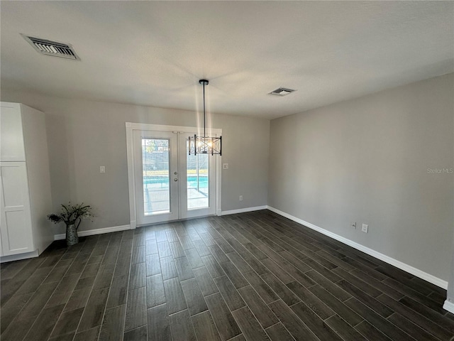 empty room with an inviting chandelier, dark wood-type flooring, and french doors