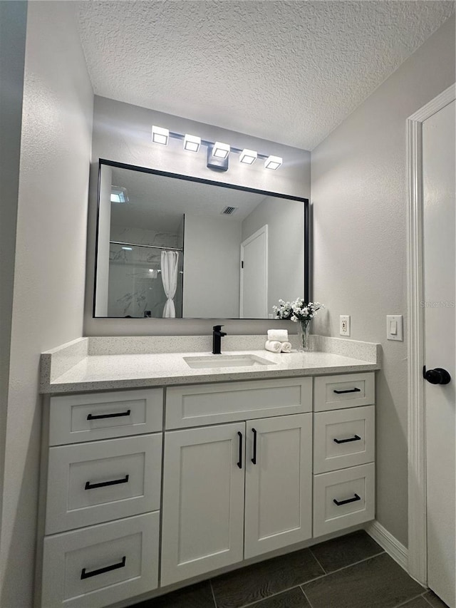 bathroom with tile patterned flooring, a shower with curtain, vanity, and a textured ceiling