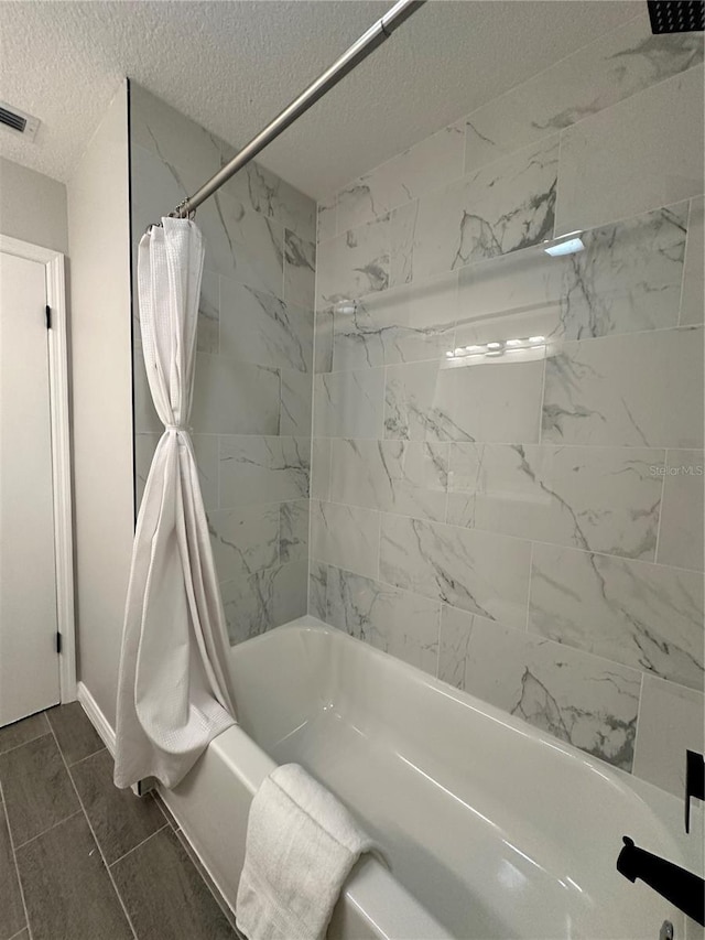 bathroom with tile patterned flooring, shower / bath combo with shower curtain, and a textured ceiling