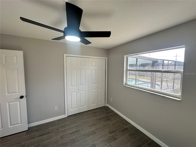 unfurnished bedroom with a textured ceiling, ceiling fan, a closet, and dark hardwood / wood-style floors