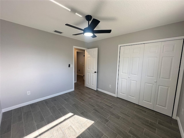 unfurnished bedroom with a textured ceiling, a closet, ceiling fan, and dark wood-type flooring