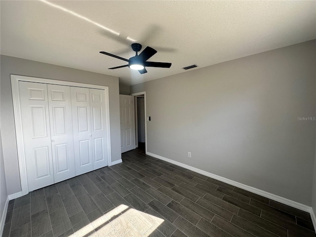 unfurnished bedroom with ceiling fan, dark hardwood / wood-style floors, a textured ceiling, and a closet