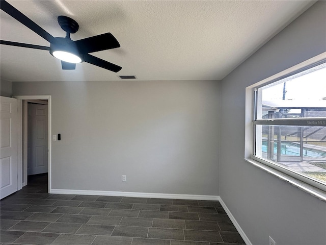 empty room with a textured ceiling and ceiling fan