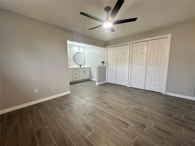 unfurnished bedroom with ensuite bath, ceiling fan, dark hardwood / wood-style flooring, and two closets