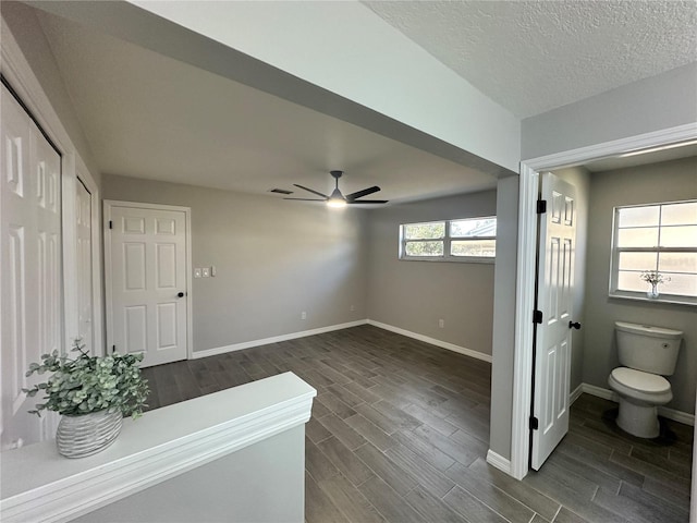 interior space with a textured ceiling, dark hardwood / wood-style flooring, and ceiling fan