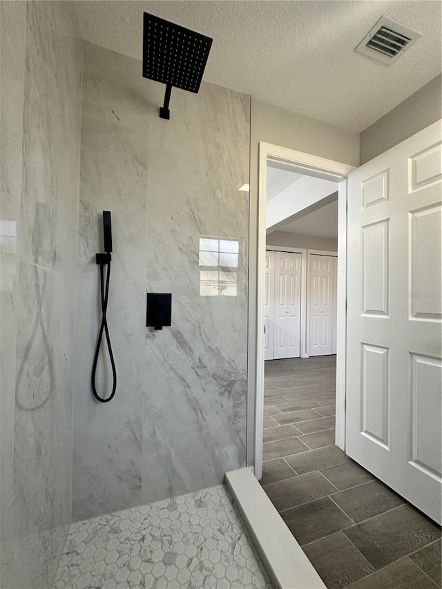 bathroom with wood-type flooring, a textured ceiling, and tiled shower