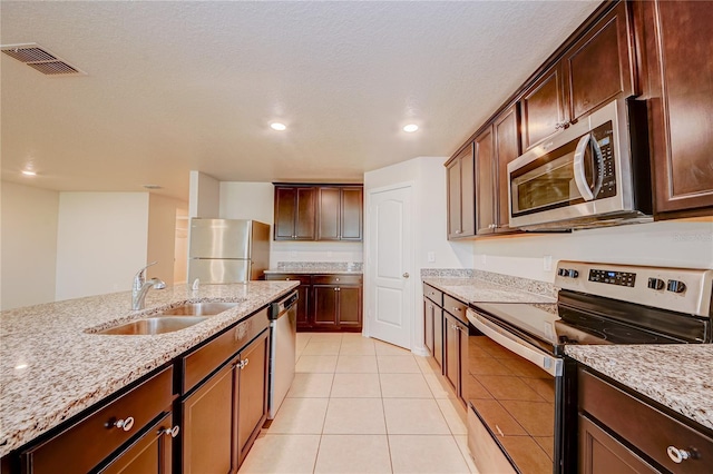 kitchen featuring stainless steel appliances, sink, light tile patterned floors, and light stone counters