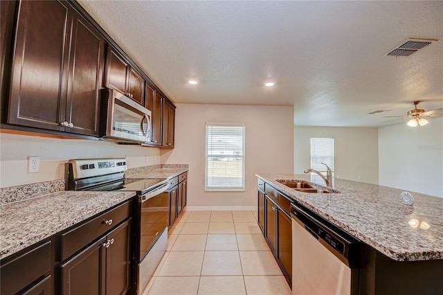 kitchen featuring light stone countertops, light tile patterned floors, appliances with stainless steel finishes, ceiling fan, and sink