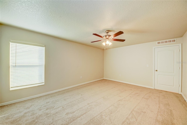 spare room with a textured ceiling, ceiling fan, and light carpet