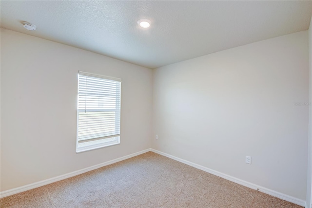 spare room with a textured ceiling and carpet