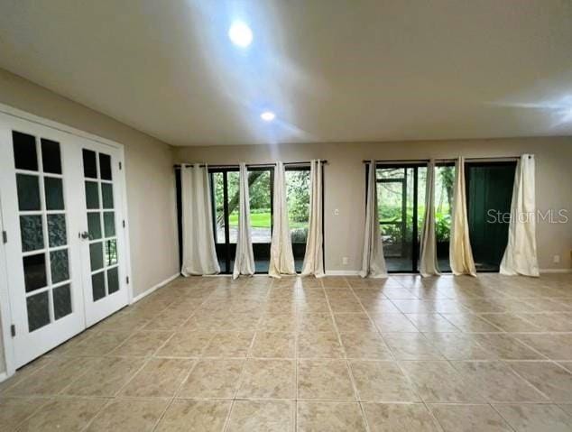 empty room featuring french doors and light tile patterned floors