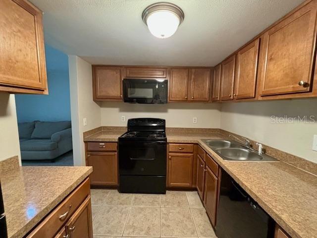 kitchen with sink, light tile patterned floors, and black appliances