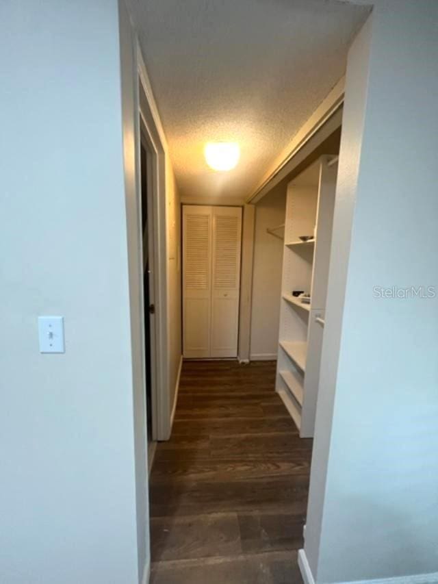 hallway featuring a textured ceiling and dark hardwood / wood-style floors