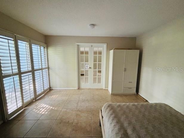 unfurnished bedroom with french doors, light tile patterned floors, and a textured ceiling