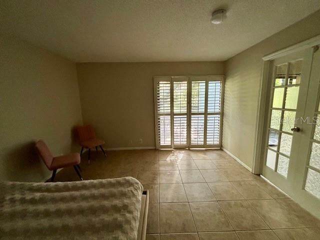 unfurnished room featuring french doors, light tile patterned floors, and a textured ceiling