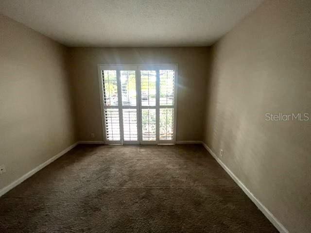 spare room featuring dark carpet and a textured ceiling