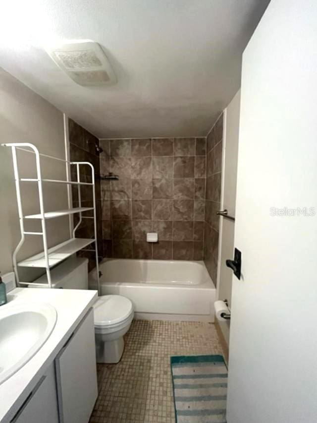 full bathroom with tiled shower / bath, vanity, and toilet