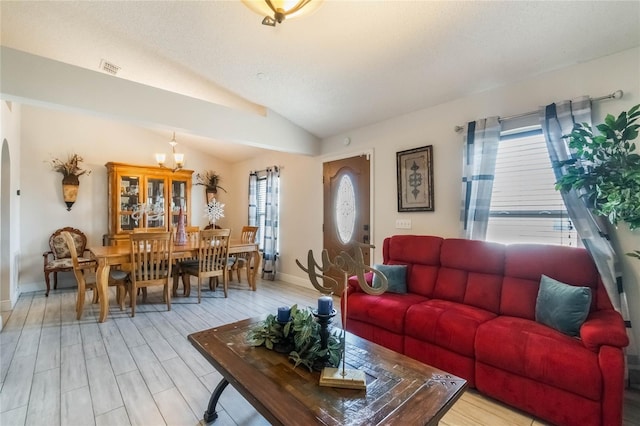 living room with light hardwood / wood-style floors, an inviting chandelier, plenty of natural light, and lofted ceiling