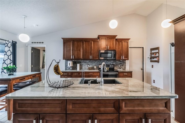 kitchen with appliances with stainless steel finishes, vaulted ceiling, and pendant lighting