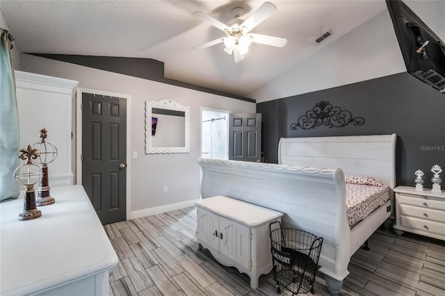 bedroom with a textured ceiling, ceiling fan, light hardwood / wood-style floors, and vaulted ceiling