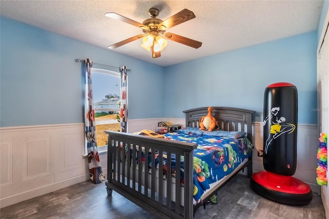 bedroom with a textured ceiling, dark hardwood / wood-style flooring, and ceiling fan