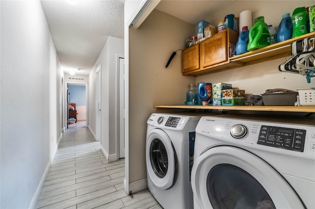 laundry area with light wood-type flooring, separate washer and dryer, and a textured ceiling