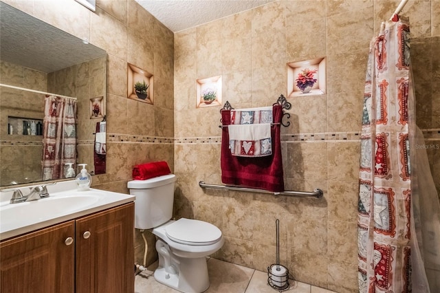 bathroom with vanity, tile patterned floors, toilet, a textured ceiling, and tile walls