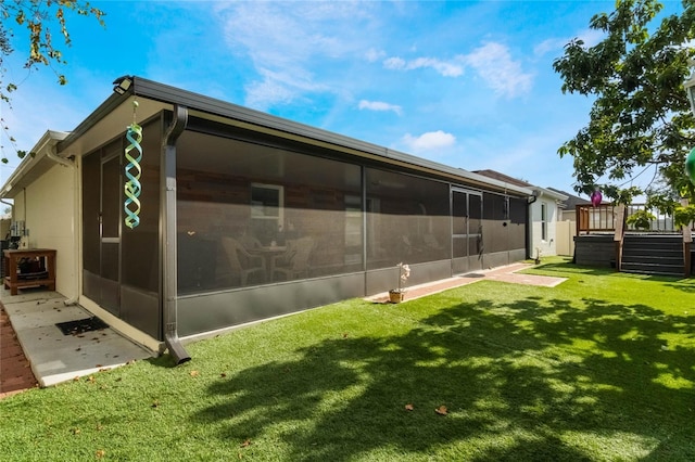 exterior space with a lawn, a wooden deck, and a sunroom