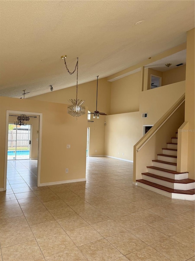 empty room featuring lofted ceiling, ceiling fan, light tile patterned floors, and a textured ceiling