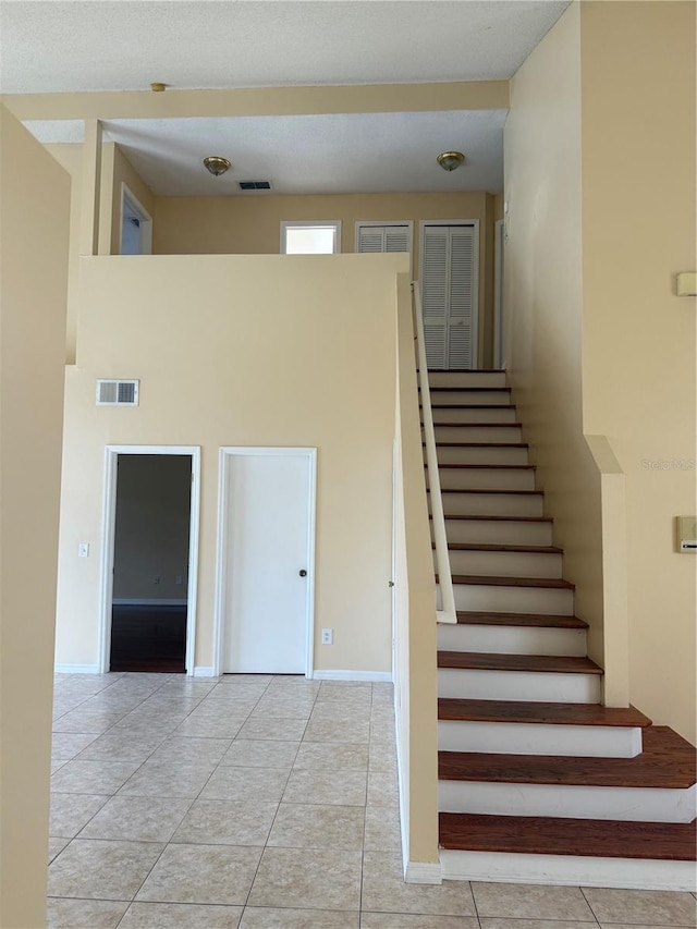 stairs featuring tile patterned flooring and a towering ceiling