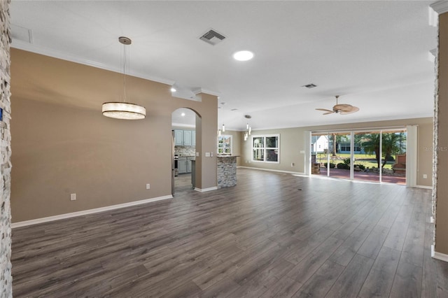 unfurnished living room with crown molding, ceiling fan, and dark wood-type flooring