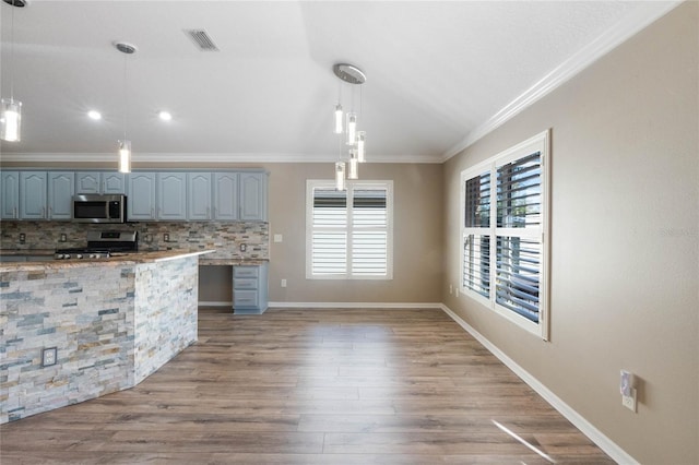 kitchen with pendant lighting, backsplash, light wood-type flooring, and stainless steel appliances