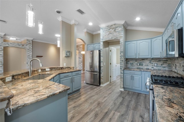 kitchen with pendant lighting, blue cabinets, sink, wood-type flooring, and stainless steel appliances