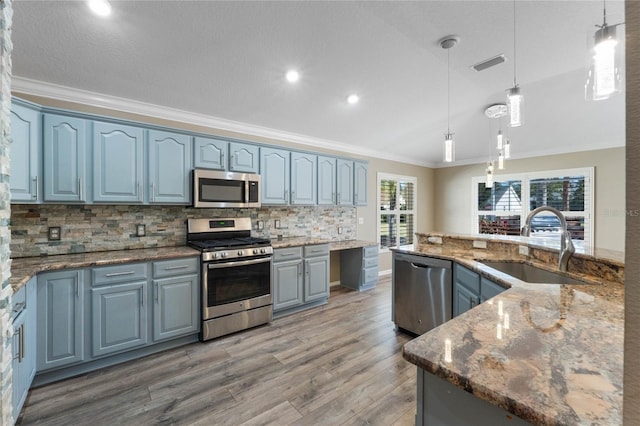 kitchen with hardwood / wood-style floors, blue cabinets, hanging light fixtures, and appliances with stainless steel finishes