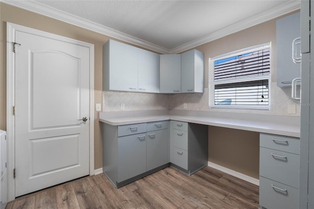 kitchen with hardwood / wood-style floors, built in desk, ornamental molding, and gray cabinetry