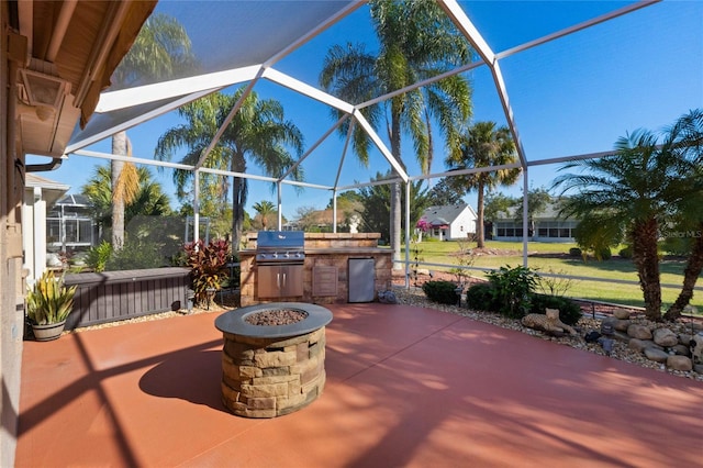 view of patio / terrace featuring a grill, an outdoor fire pit, a lanai, and exterior kitchen