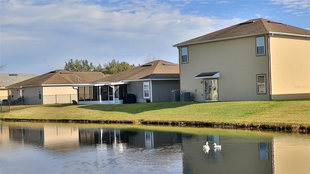 rear view of property featuring a sunroom, a yard, a water view, and central AC unit