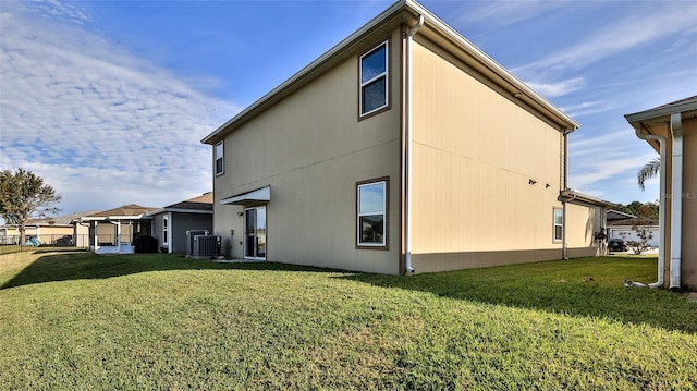 rear view of house featuring a yard and central air condition unit