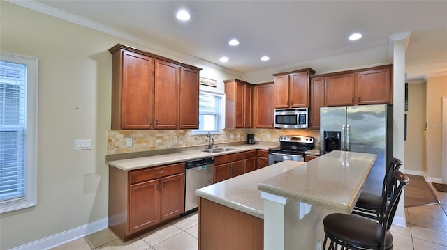 kitchen with a breakfast bar, a center island, sink, crown molding, and stainless steel appliances