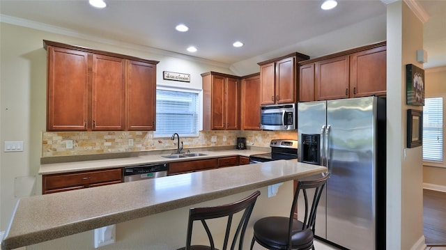 kitchen with tasteful backsplash, stainless steel appliances, crown molding, sink, and a breakfast bar area