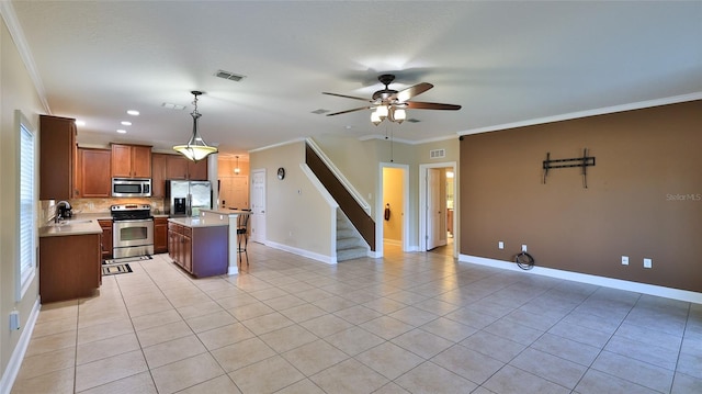 kitchen with appliances with stainless steel finishes, ornamental molding, ceiling fan, decorative light fixtures, and a center island