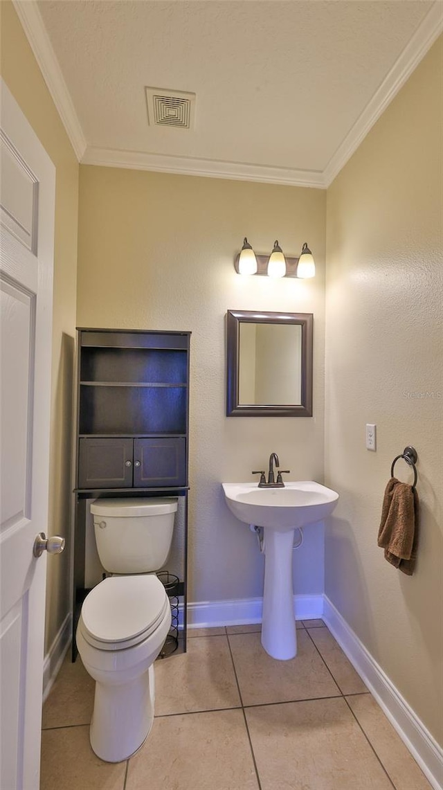 bathroom with tile patterned flooring, toilet, and crown molding