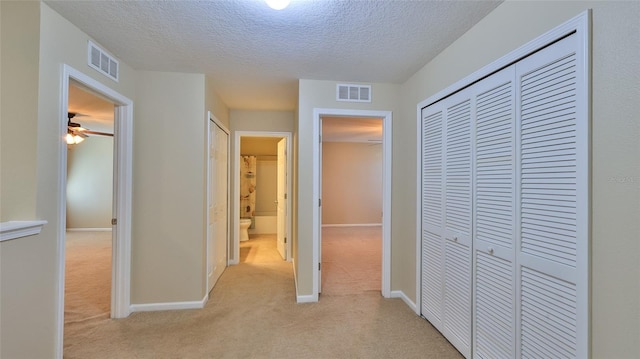 hall with a textured ceiling and light carpet