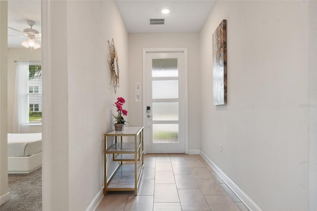 doorway featuring ceiling fan and light tile patterned flooring