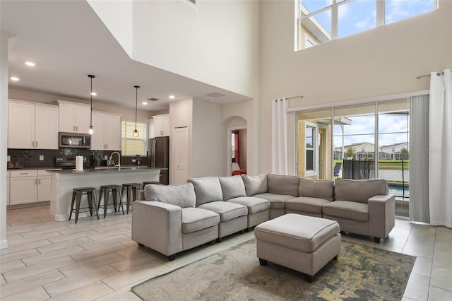 8942 Cabot Cliffs Dr, Davenport, FL 33896 - living room featuring healthy amount of natural light, a high ceiling, arched walkways, and recessed lighting