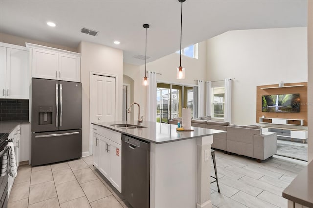 8942 Cabot Cliffs Dr, Davenport, FL 33896 - kitchen with stainless steel appliances, white cabinets, open floor plan, a kitchen island with sink, and hanging light fixtures