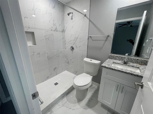 bathroom with vanity, ceiling fan, toilet, and tiled shower