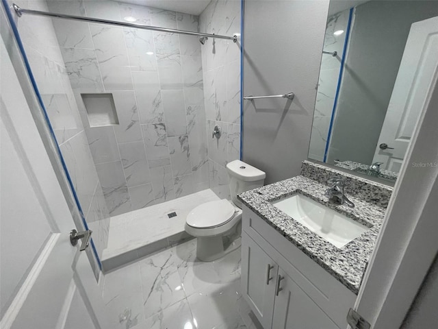 bathroom with tiled shower, vanity, and toilet