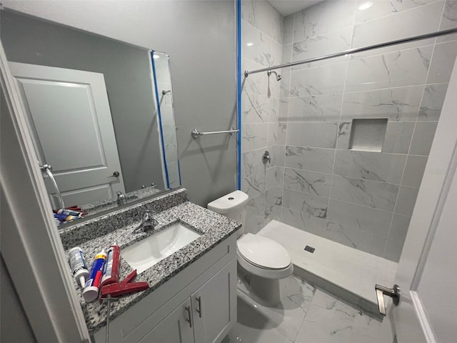 bathroom with tiled shower, vanity, and toilet